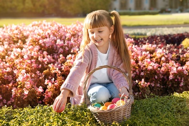 Photo of Cute little girl with basket of Easter eggs in park