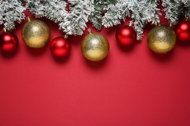 Photo of Christmas balls and fir tree branches with snow on red background, flat lay. Space for text