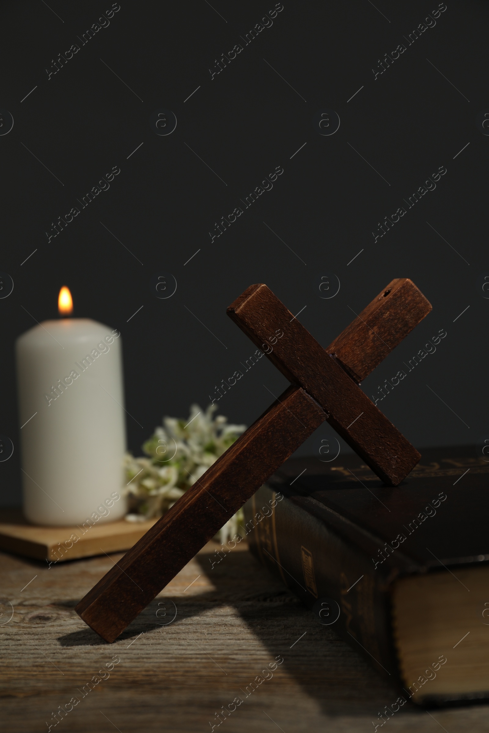Photo of Cross, Bible, church candle and flowers on wooden table