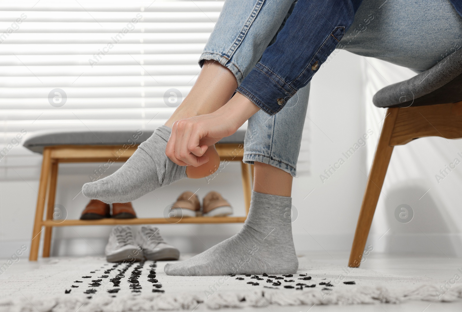 Photo of Woman putting on grey socks at home, closeup