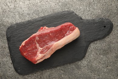 Photo of Piece of raw beef meat on grey textured table, top view