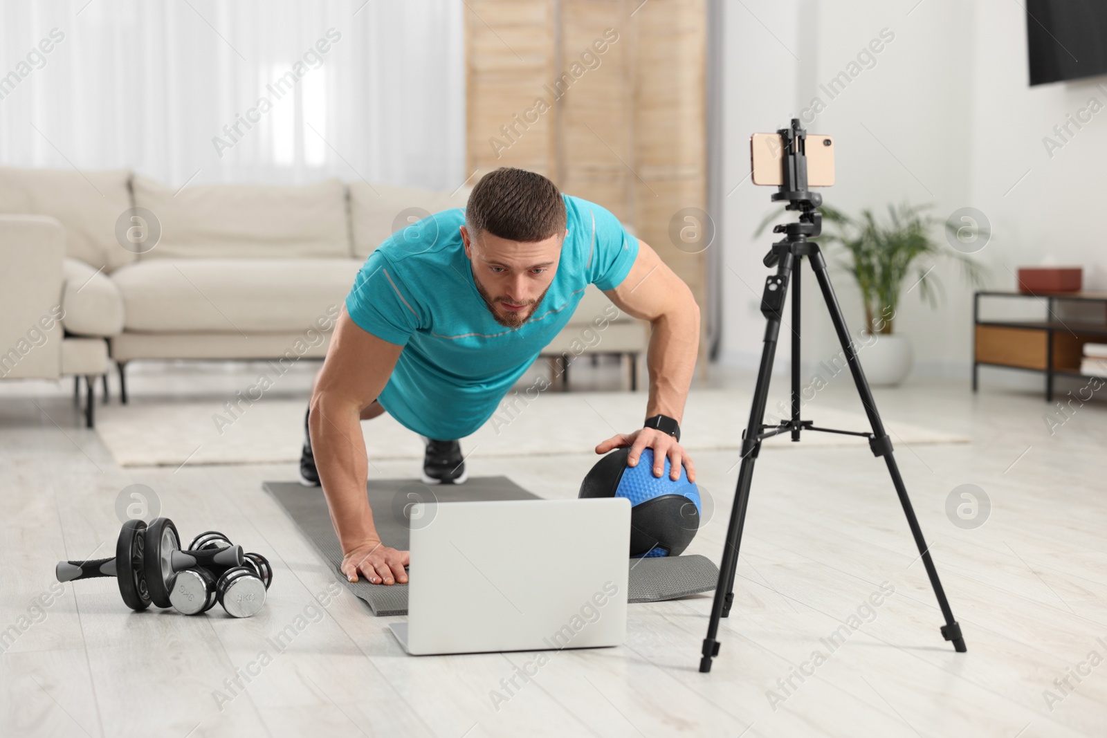 Photo of Trainer with ball streaming online workout on phone at home