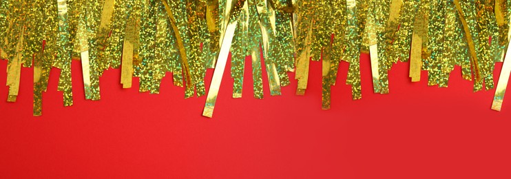 Golden tinsel on red background, top view. Banner design