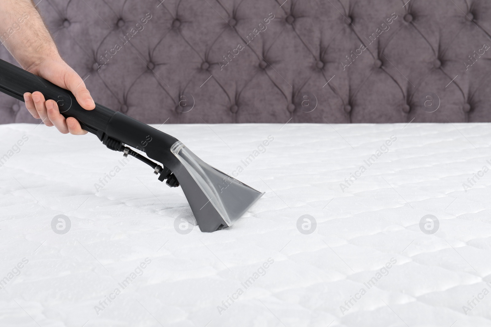 Photo of Man disinfecting mattress with vacuum cleaner, closeup. Space for text