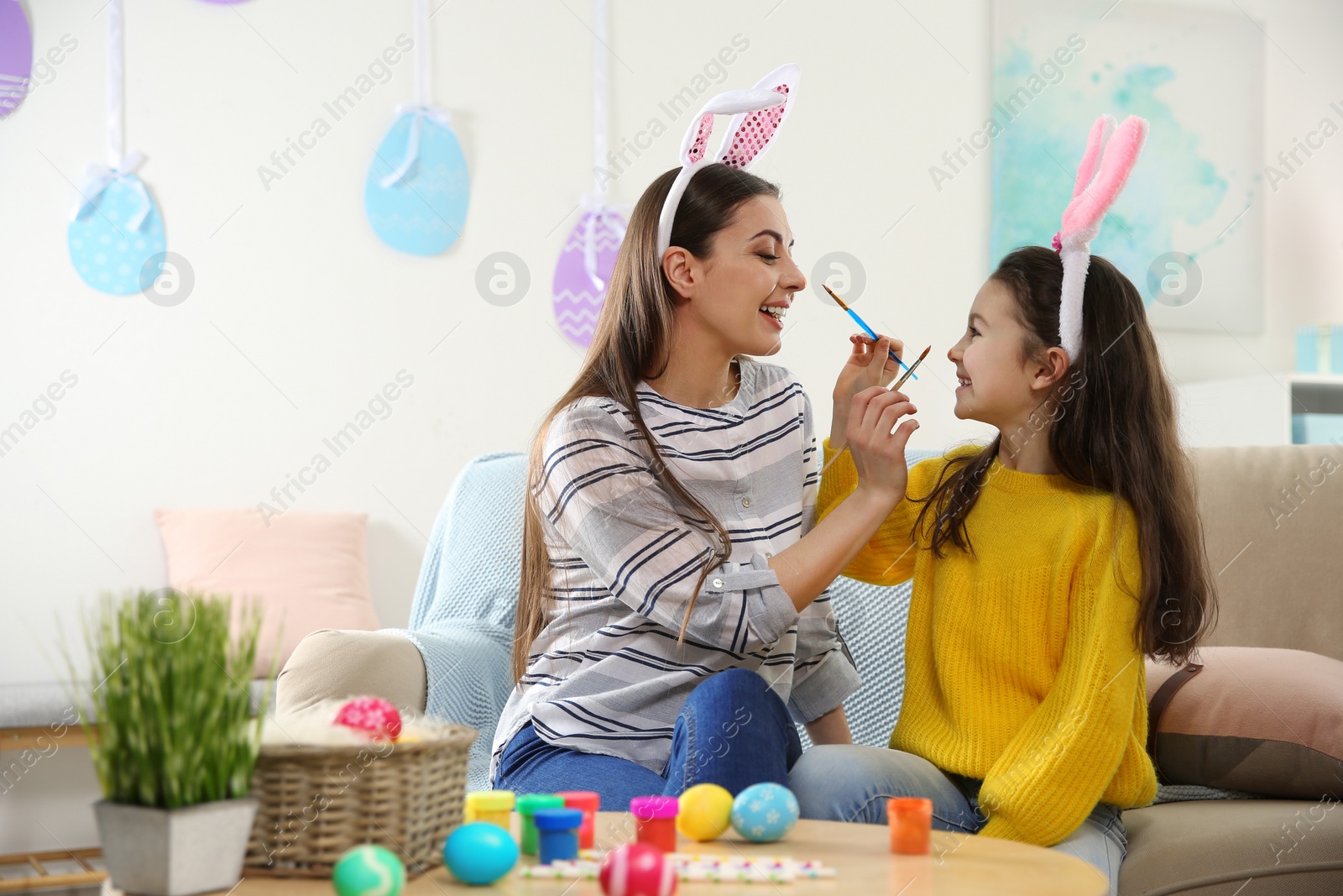 Photo of Mother and daughter with bunny ears headbands having fun at home, space for text. Easter holiday