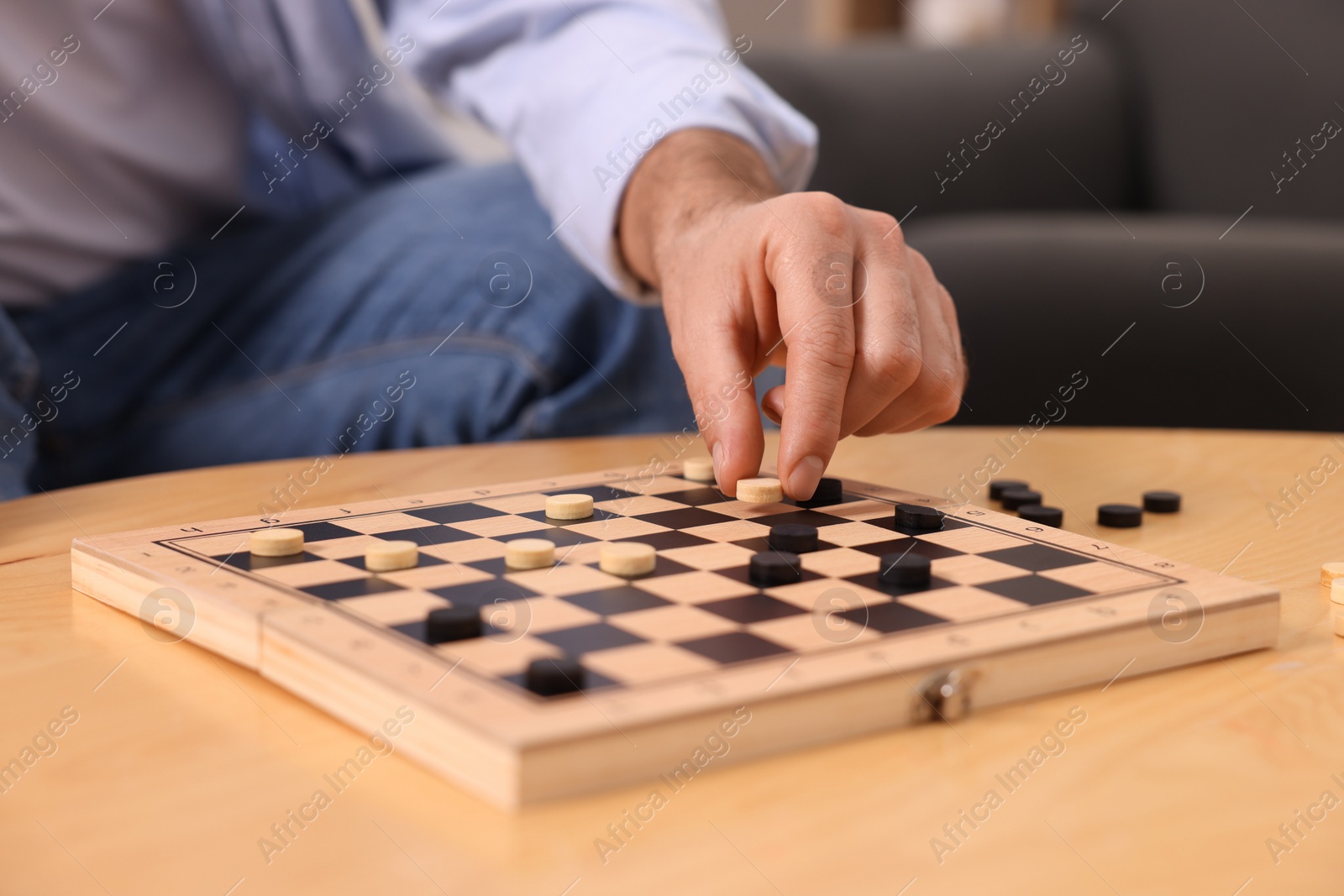 Photo of Man playing checkers at wooden table, closeup