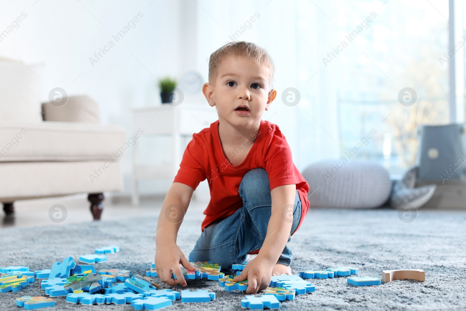 Photo of Cute little child playing with puzzles on floor indoors