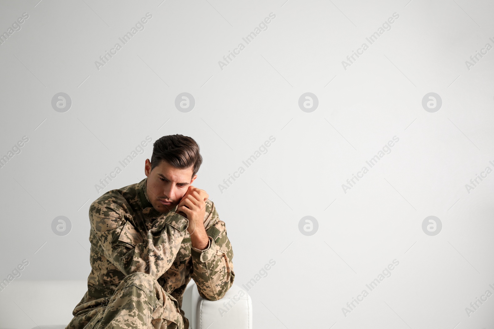 Photo of Stressed military officer sitting on sofa against white background. Space for text