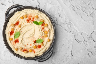 Photo of Delicious hummus with chickpeas and paprika on white textured table, top view. Space for text
