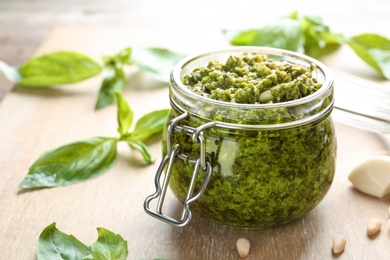 Photo of Jar of tasty pesto sauce on table, closeup. Space for text