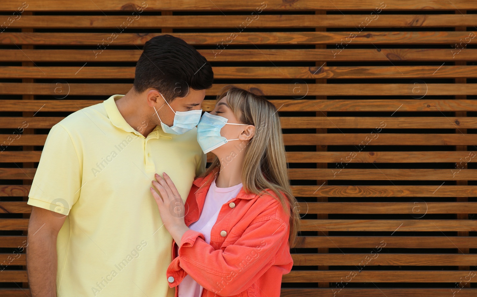 Photo of Couple in medical masks trying to kiss outdoors