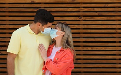 Couple in medical masks trying to kiss outdoors