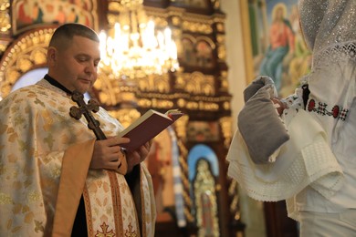 Photo of Stryi, Ukraine - September 11, 2022: Priest conducting baptism ceremony in Assumption of Blessed Virgin Mary cathedral
