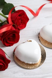 Photo of St. Valentine's Day. Delicious heart shaped cakes and roses on white wooden table