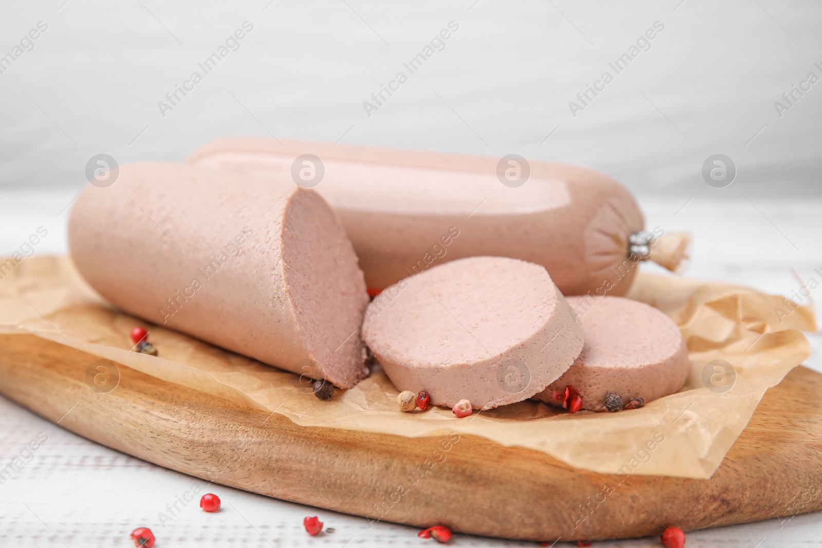 Photo of Board with delicious liver sausage on white wooden table, closeup