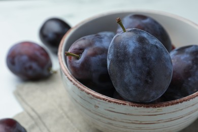 Photo of Tasty ripe plums in bowl on table, closeup