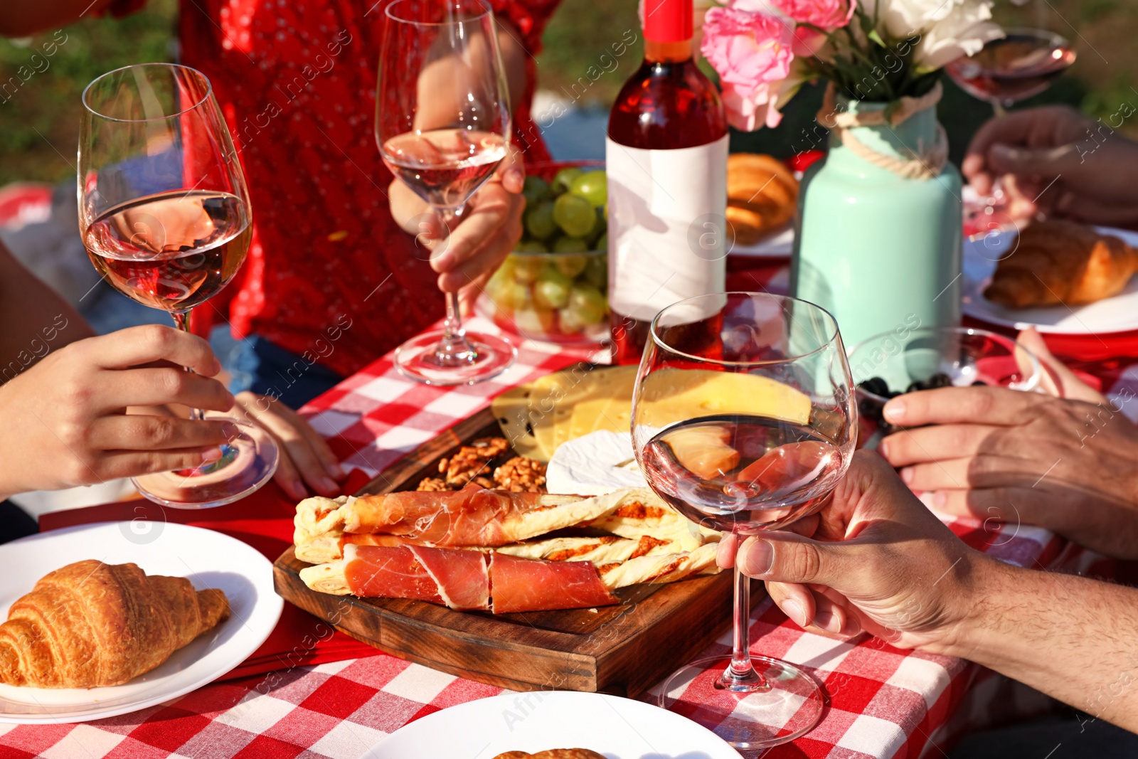 Photo of Group of people having picnic at table outdoors, closeup