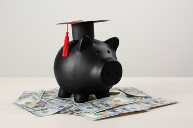 Photo of Scholarship concept. Piggy bank, graduation cap and banknotes on white wooden table