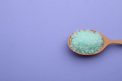 Photo of Spoon with turquoise sea salt on violet background, top view. Space for text