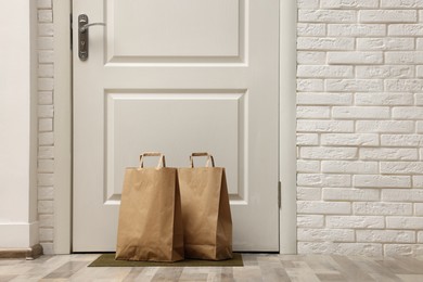 Photo of Paper bags on door mat near entrance, space for text