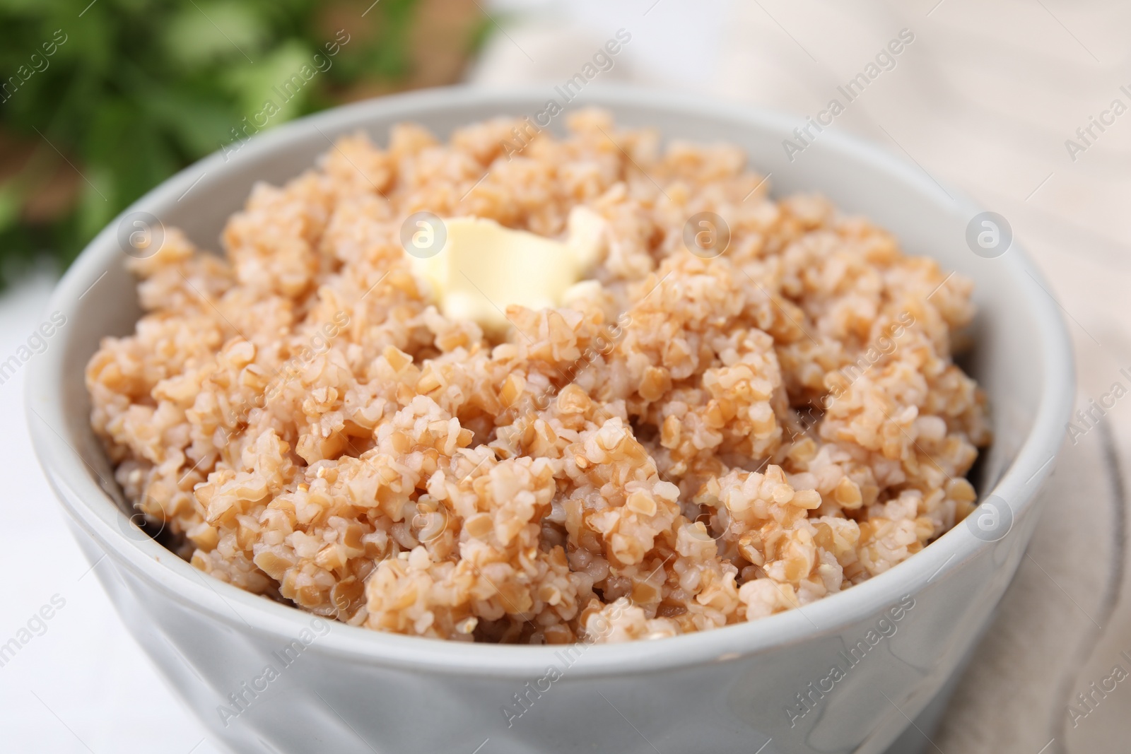 Photo of Tasty wheat porridge with butter in bowl on table, closeup