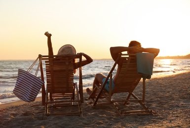 Young couple relaxing in deck chairs on beach near sea