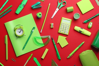 Photo of Green school stationery on red background, flat lay