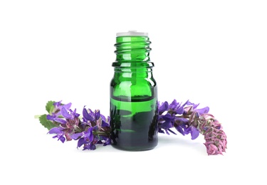 Photo of Bottle of herbal essential oil and sage flowers isolated on white