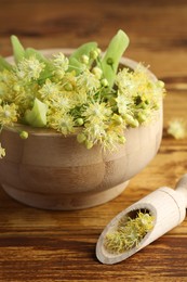 Photo of Fresh linden leaves and flowers on wooden table, closeup