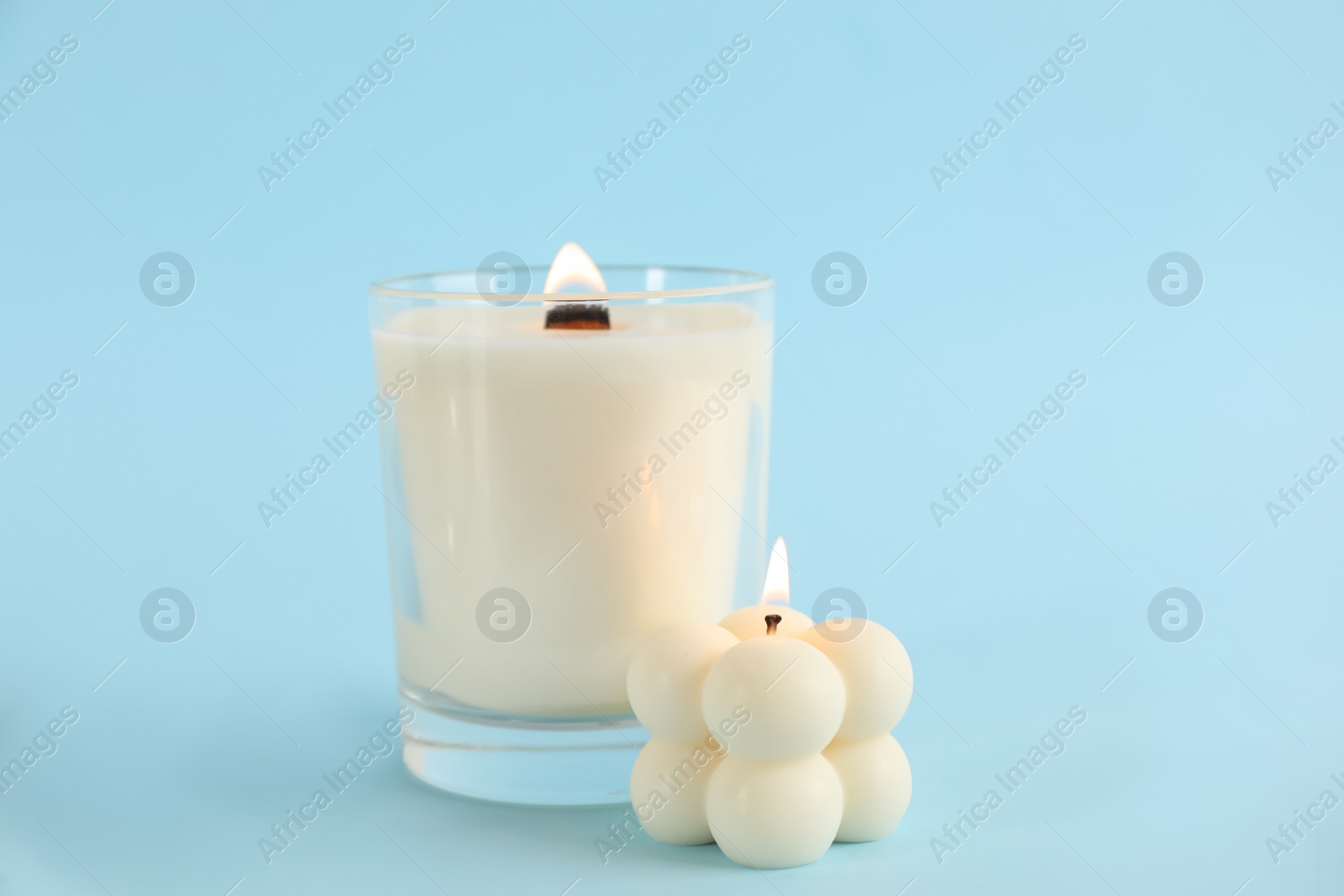 Photo of Burning soy candles on light blue background