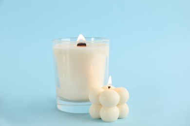 Photo of Burning soy candles on light blue background