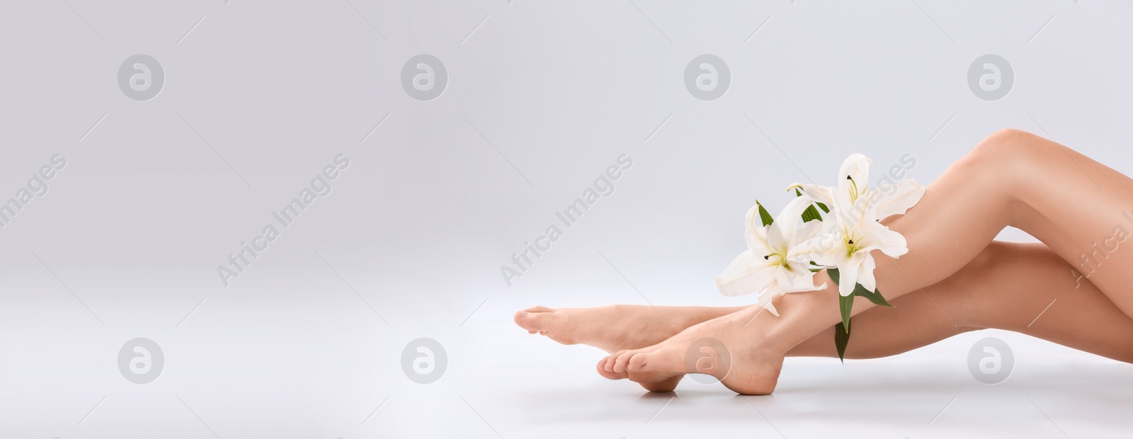 Image of Young woman with silky skin and flowers on light background, closeup view with space for text. Banner design