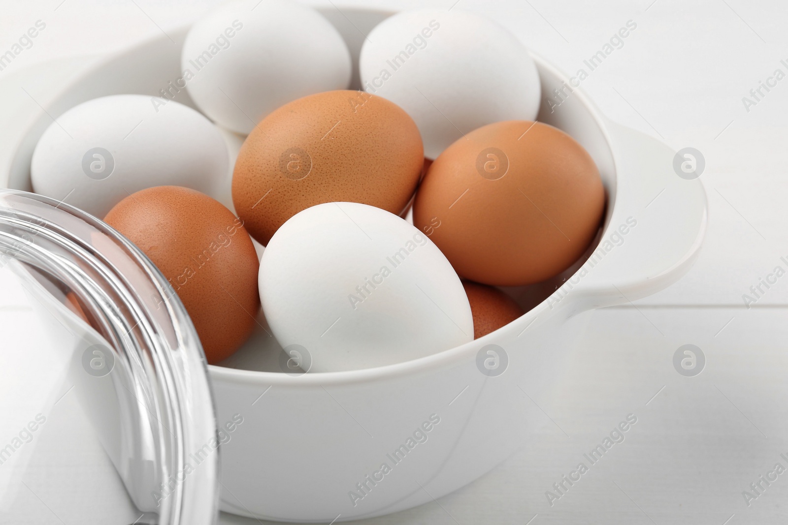 Photo of Unpeeled boiled eggs in saucepan on white table, closeup