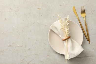 Stylish setting with cutlery, napkin, dry branch and plate on light table, top view. Space for text