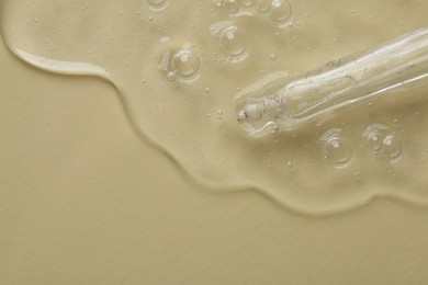 Pipette with cosmetic serum on beige background, top view. Space for text