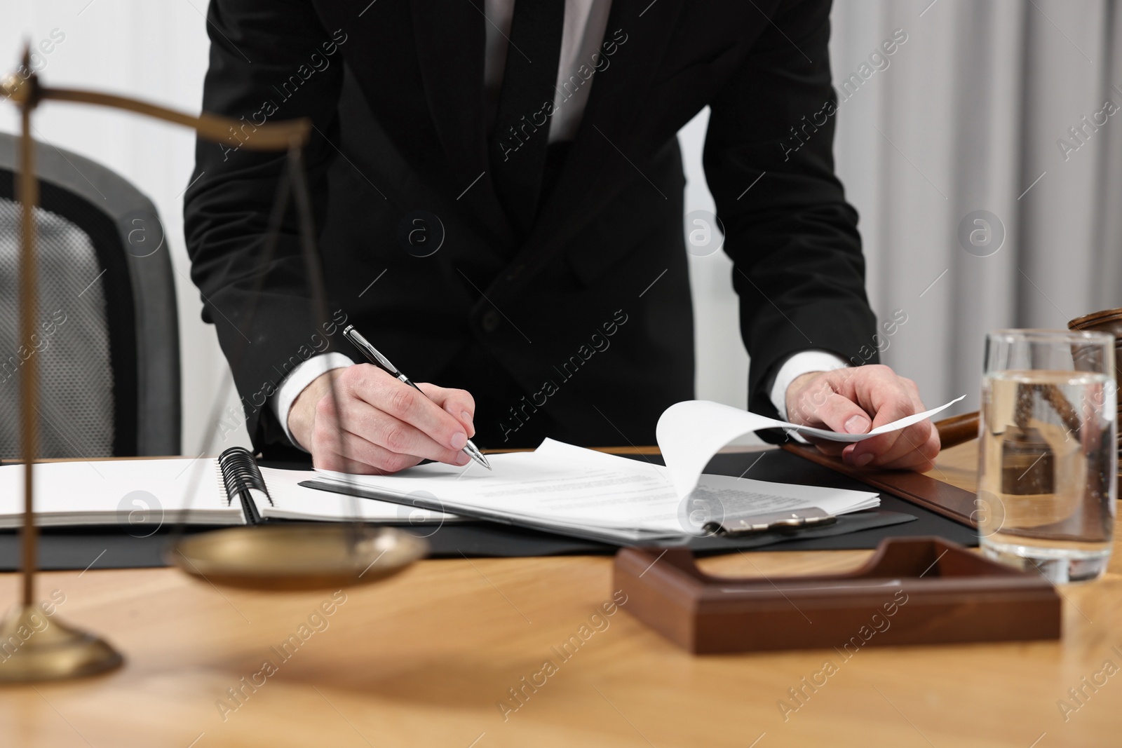 Photo of Lawyer working with documents at wooden table indoors, closeup