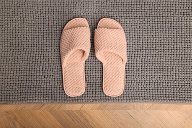 Photo of Soft grey bath mat and slippers on floor, top view