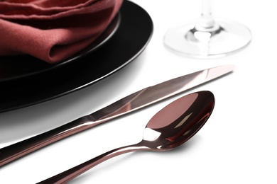 Photo of Elegant shiny cutlery near plates on white background, closeup