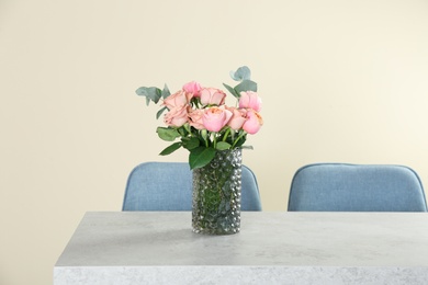 Photo of Vase with beautiful flowers as element of interior design on table in room