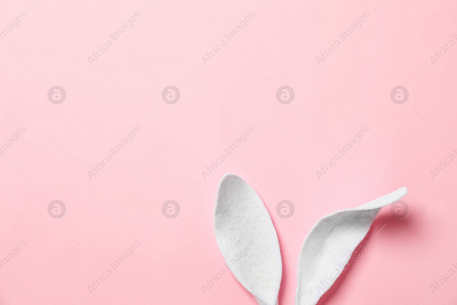 Photo of Funny Easter bunny ears on color background, top view with space for text