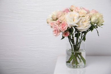 Beautiful rose flowers in vase on white table indoors, space for text