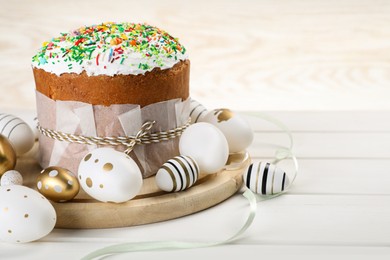 Photo of Traditional Easter cake with sprinkles and painted eggs on white wooden table, space for text