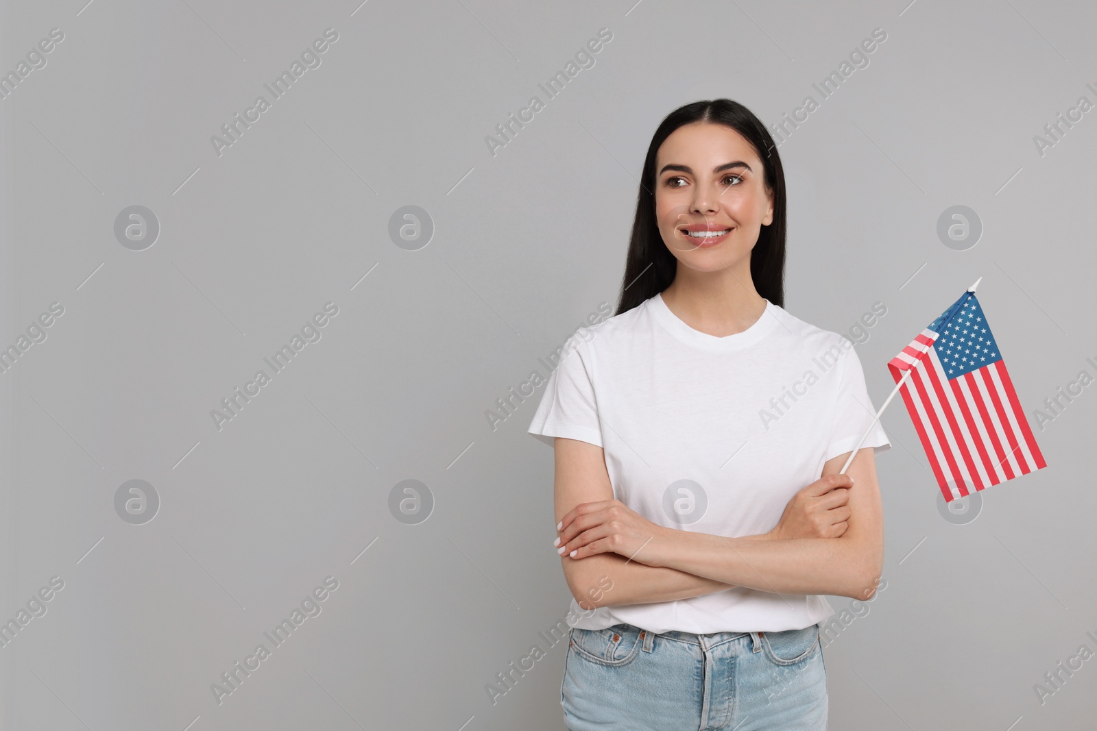 Photo of 4th of July - Independence Day of USA. Happy woman with American flag on light grey background, space for text