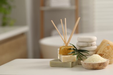 Composition with different spa products and palm leaves on white table in bathroom, space for text