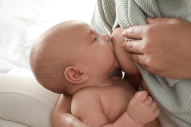 Photo of Young woman breastfeeding her little baby at home, closeup