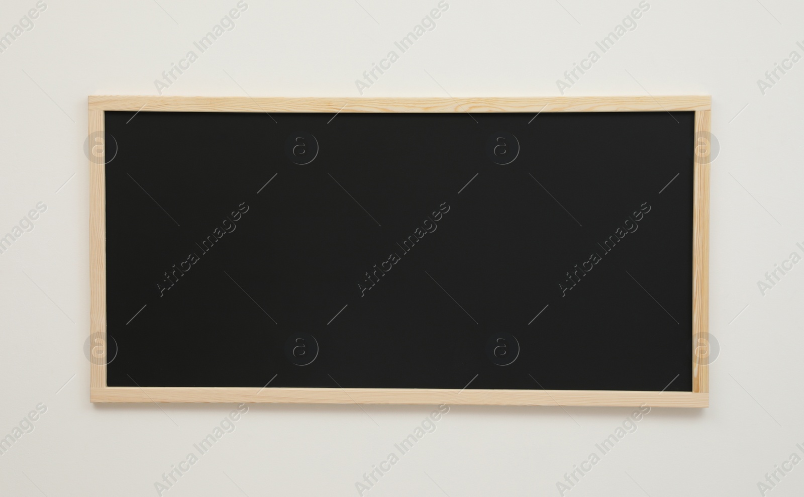 Photo of Clean black chalkboard hanging on white wall