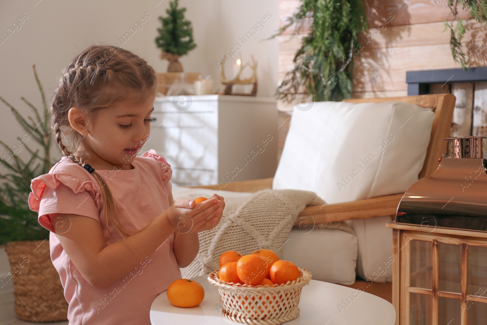 Photo of Cute little child with fresh tangerines at home