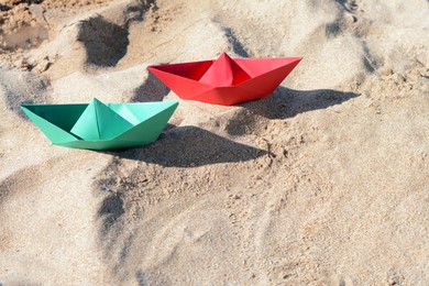 Two color paper boats on sandy beach, above view. Space for text