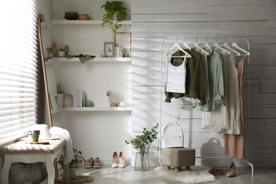 Rack with different stylish clothes, shoes and decorative elements in dressing room. Interior design