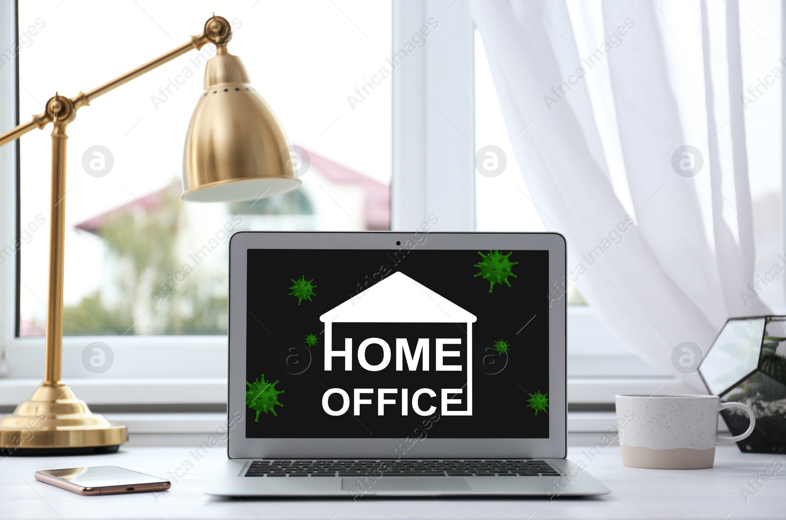 Image of Modern laptop with text HOME OFFICE on white table indoors